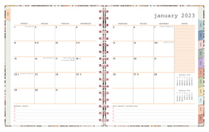 Jan 2023 - Dec 2023 WAAV planner 7x9 planner featuring a monthly spread with empty white boxes, lined notes section with reference calendars, monthly goals and priorities, multi-colored monthly tabs and pink spiral bound.