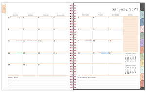 Jan 2023 - Dec 2023 WAAV planner 8.5x11 planner featuring a monthly spread with empty white boxes, lined notes section with reference calendars, monthly goals and priorities, multi-colored monthly tabs and pink spiral bound.