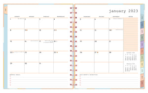 Jan 2023 - Dec 2023 WAAV planner 7x9 planner featuring a monthly spread with empty white boxes, lined notes section with reference calendars, monthly goals and priorities, multi-colored monthly tabs and pink spiral bound.