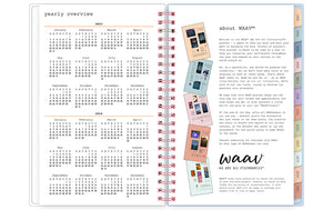 the 2023 waav planner in 5x8 size includes a ruler, sticker sheet, pocket, and multi-colored monthly tabs and pink spiral binding.
