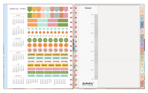 the 2023 waav planner in 7x9 size includes a ruler, sticker sheet, pocket, and multi-colored monthly tabs and pink spiral binding.